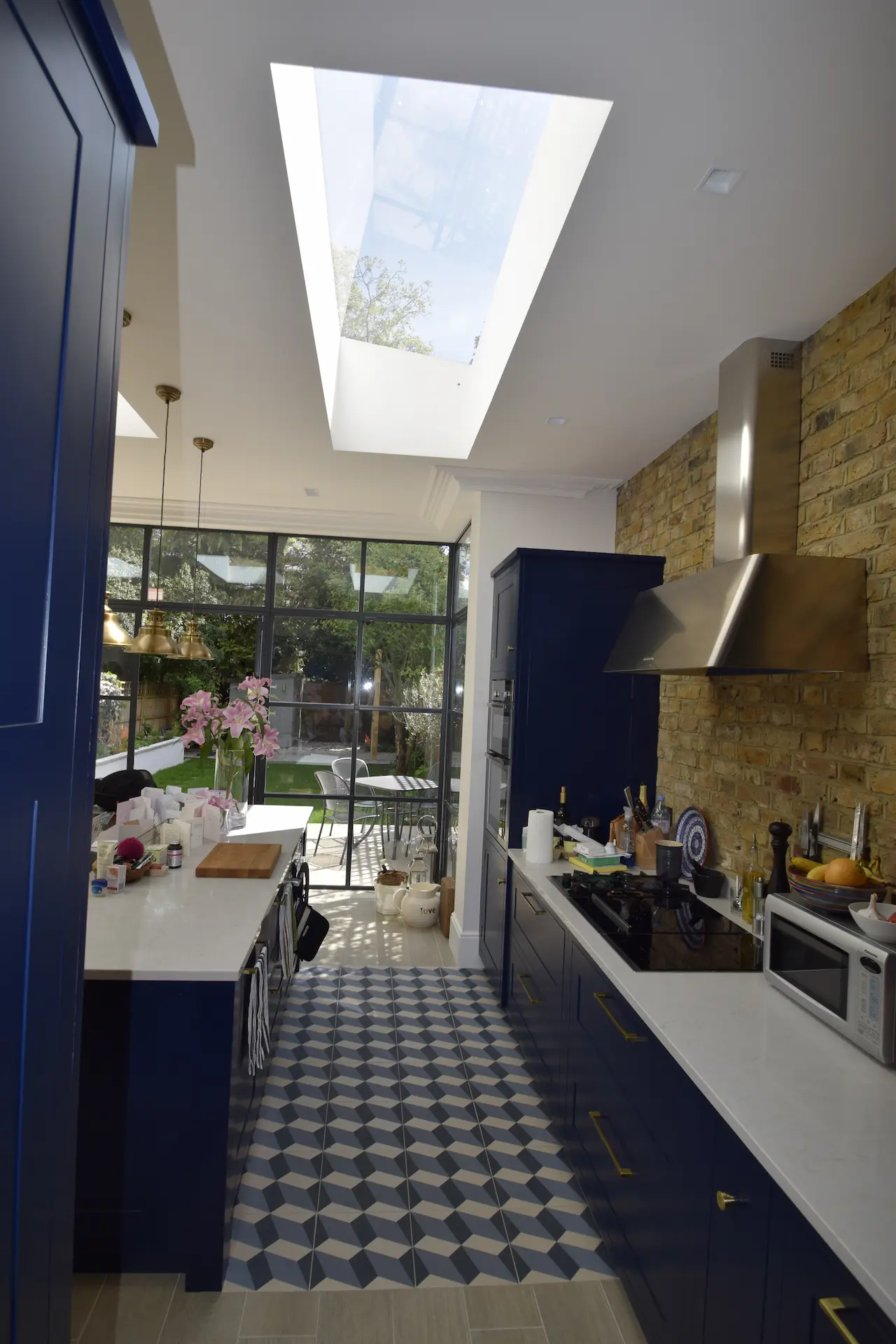 Beautiful kitchen in an Ealing ground floor extension featuring blue kitchen units and patterned tiles on the floor