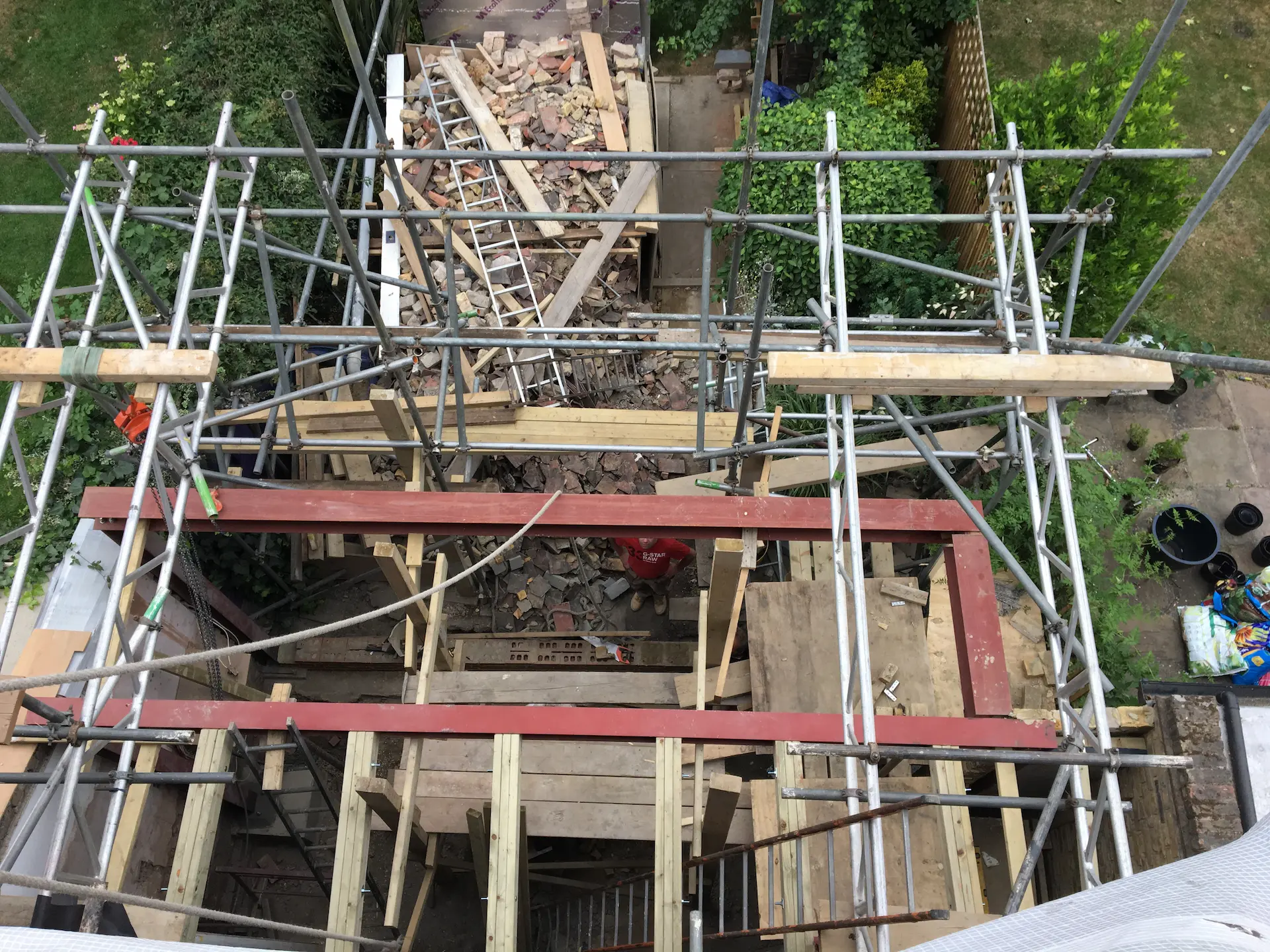 Top-down view of steel beam, trimmers, and scaffold during ground floor extension in Ealing
